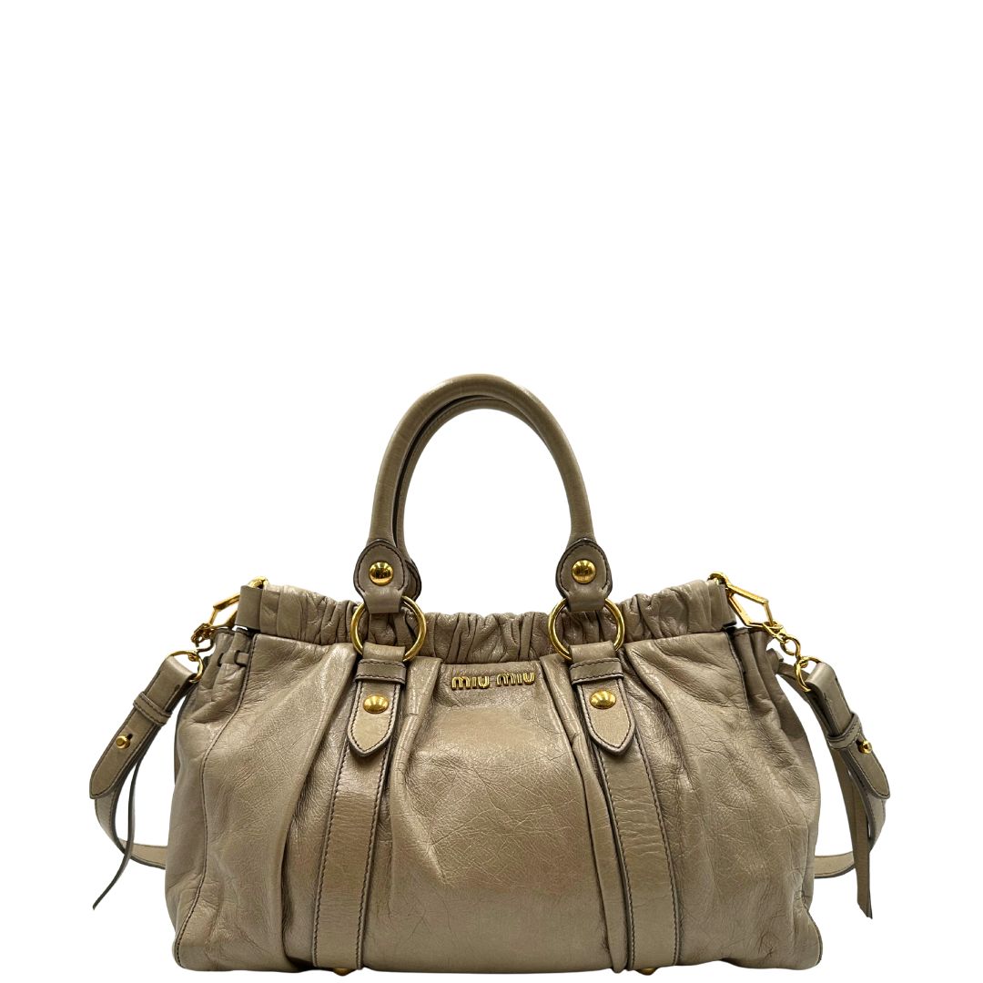 front Borsa Miu Miu in pelle beige con parti metalliche dorate; munita di una tracolla e doppi manici stondati. Completa di dustbag, di lusso, originale, ottime condizioni. 