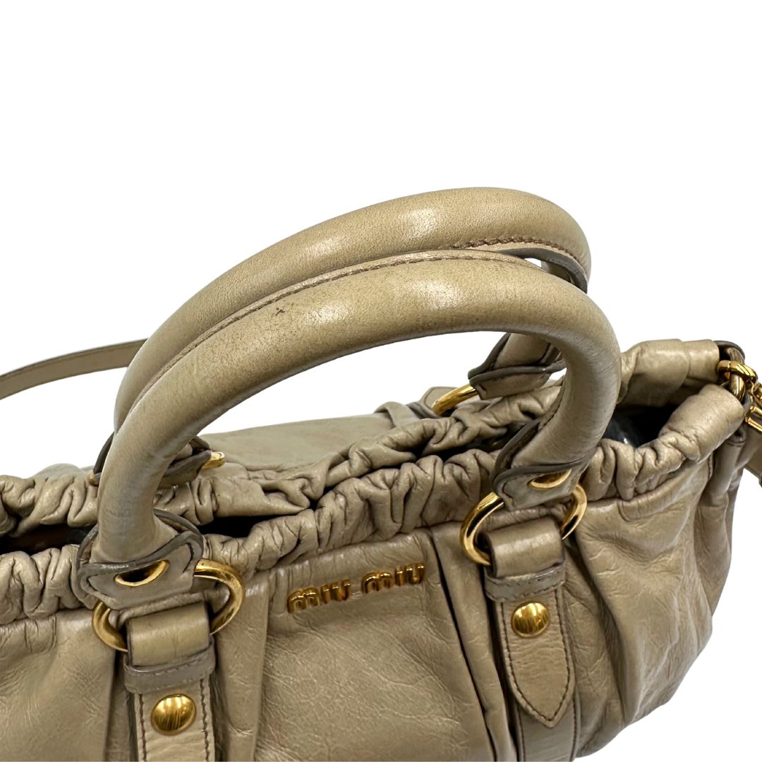 manici Borsa Miu Miu in pelle beige con parti metalliche dorate; munita di una tracolla e doppi manici stondati. Completa di dustbag, di lusso, originale, ottime condizioni. 