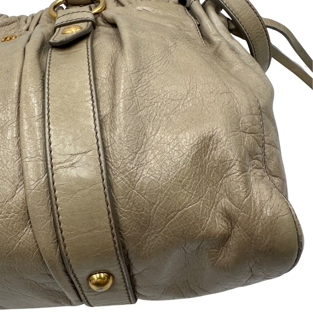 angolo Borsa Miu Miu in pelle beige con parti metalliche dorate; munita di una tracolla e doppi manici stondati. Completa di dustbag, di lusso, originale, ottime condizioni. 