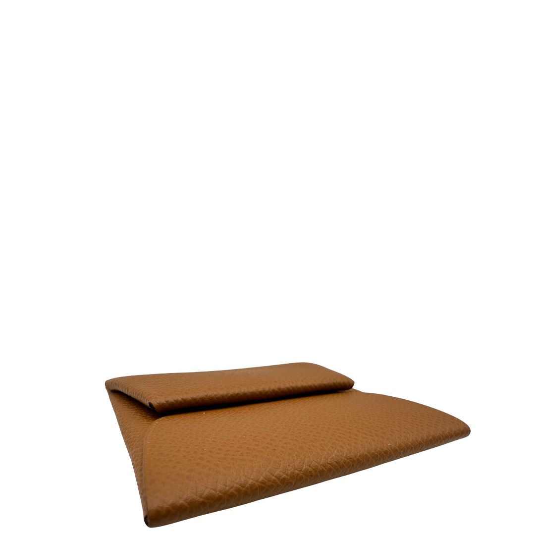 Base di un mini portamonete Hermès in pelle color cammello, con chiusura a bottone. Completo di scatola.