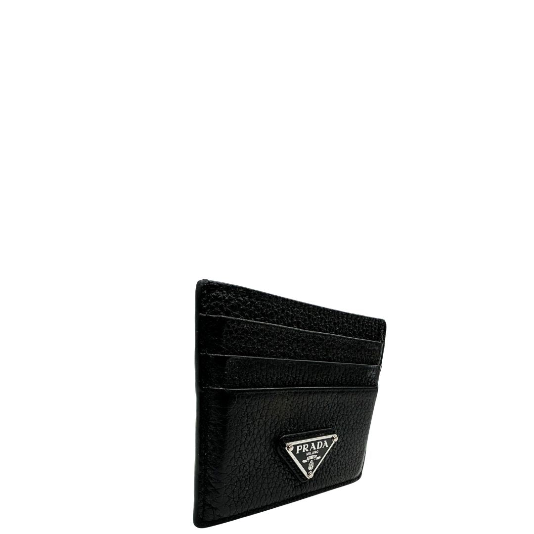 Portacarte Prada nera con parti metalliche argentate; impreziosito da iconico logo sul front. Completa di scatola, di lusso, originale, ottime condizioni, usato.