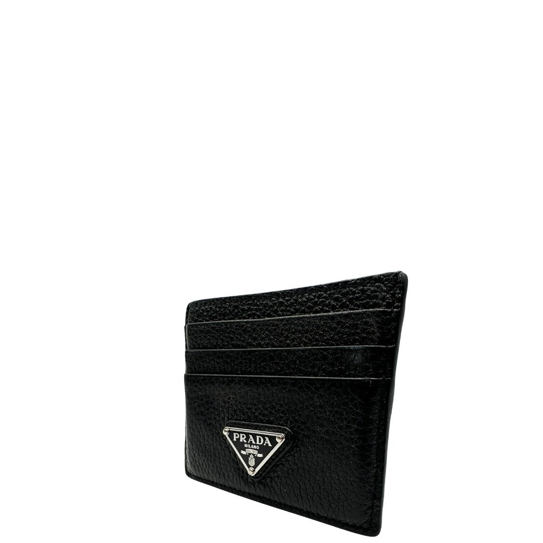 Portacarte Prada nera con parti metalliche argentate; impreziosito da iconico logo sul front. Completa di scatola, di lusso, originale, ottime condizioni, usato.