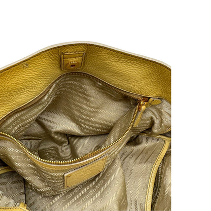 Interno di una Borsa Prada in pelle lucida color mustard con parti metalliche dorate; munita di un accessorio porta address e doppi manici stondati. Indossabile a mano oppure a tracolla. Originale, usata, di lusso, in ottime condizioni