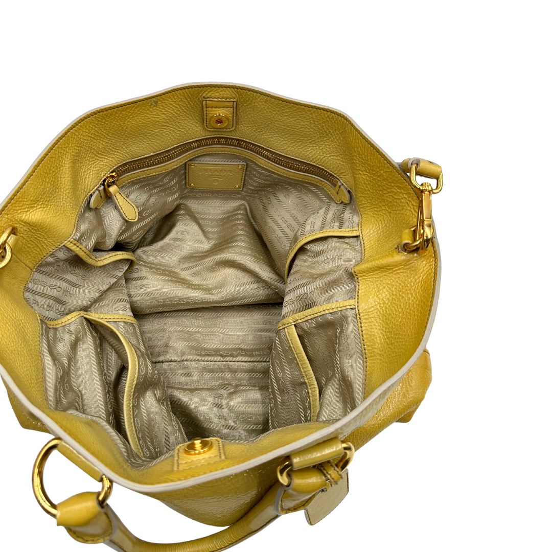 Interno di una Borsa Prada in pelle lucida color mustard con parti metalliche dorate; munita di un accessorio porta address e doppi manici stondati. Indossabile a mano oppure a tracolla. Originale, usata, di lusso, in ottime condizioni