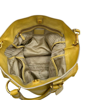 Interno di una Borsa Prada in pelle lucida color mustard con parti metalliche dorate; munita di un accessorio porta address e doppi manici stondati. Indossabile a mano oppure a tracolla. Originale, usata, di lusso, in ottime condizioni
