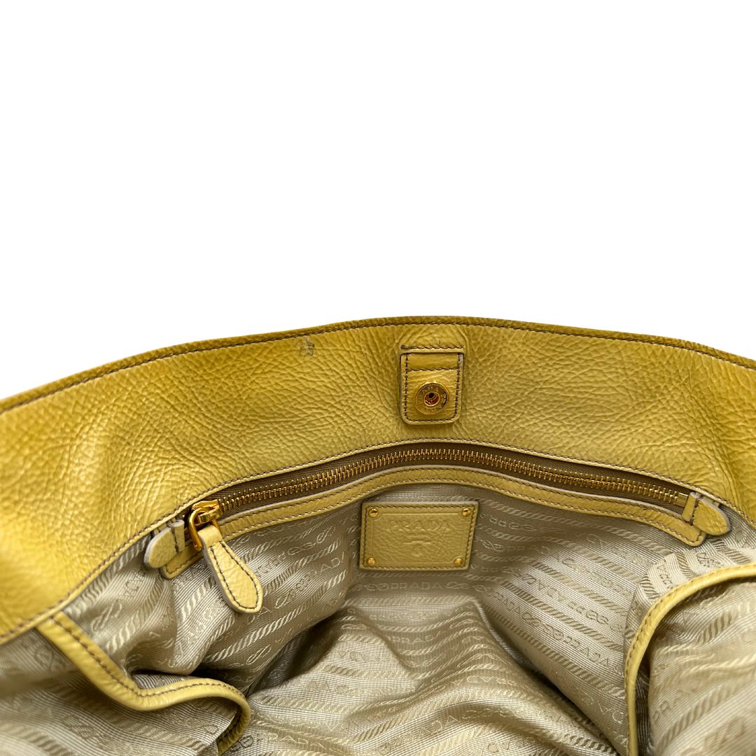 Interno di una Borsa Prada in pelle lucida color mustard con parti metalliche dorate; munita di un accessorio porta address e doppi manici stondati. Indossabile a mano oppure a tracolla. Originale, usata, di lusso, in ottime condizioni