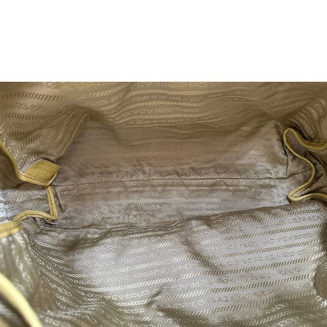 Interno di una Borsa Prada in pelle lucida color mustard con parti metalliche dorate; munita di un accessorio porta address e doppi manici stondati. Indossabile a mano oppure a tracolla. Originale, usata, di lusso, in ottime condizioni