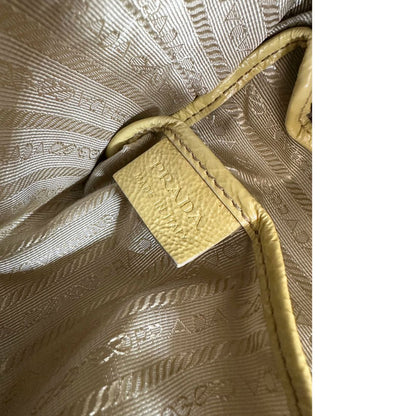 Interno di una Borsa Prada in pelle lucida color mustard con parti metalliche dorate; munita di un accessorio porta address e doppi manici stondati. Indossabile a mano oppure a tracolla. Originale, usata, di lusso, in ottime condizioni