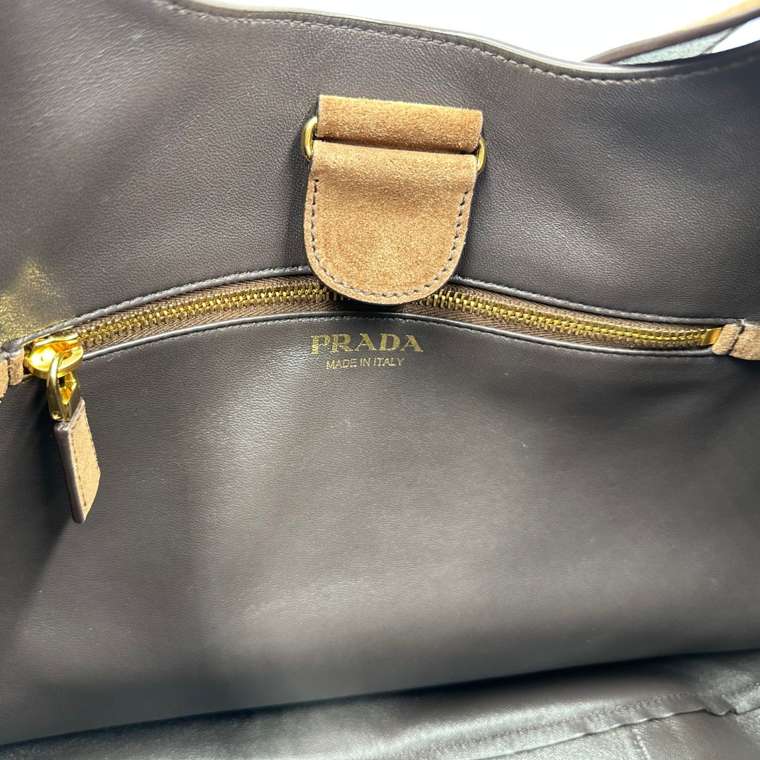 interno Borsa Prada in pelle scamosciata marrone con parti metalliche dorate; munita di un manico singolo regolabile; indossabile a spalla o a tracolla. Completa di dustbag, di lusso, originale, ottime condizioni, usata. 