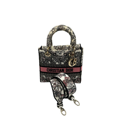 Borsa Dior in realizzata in tessuto jacquard con motivo Toile de Jouy nei toni del nero, beige e rosa e metalleria dorata, munita di due manici rigidi e una tracolla logata amovibile. Da indossare a tracolla o a mano. Completa di dustbag e cartellino, di lusso, usata, originale, ottime condizioni.