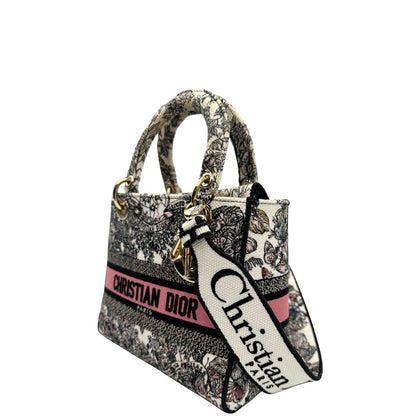 lato Borsa Dior in realizzata in tessuto jacquard con motivo Toile de Jouy nei toni del nero, beige e rosa e metalleria dorata, munita di due manici rigidi e una tracolla logata amovibile. Da indossare a tracolla o a mano. Completa di dustbag e cartellino, di lusso, usata, originale, ottime condizioni.