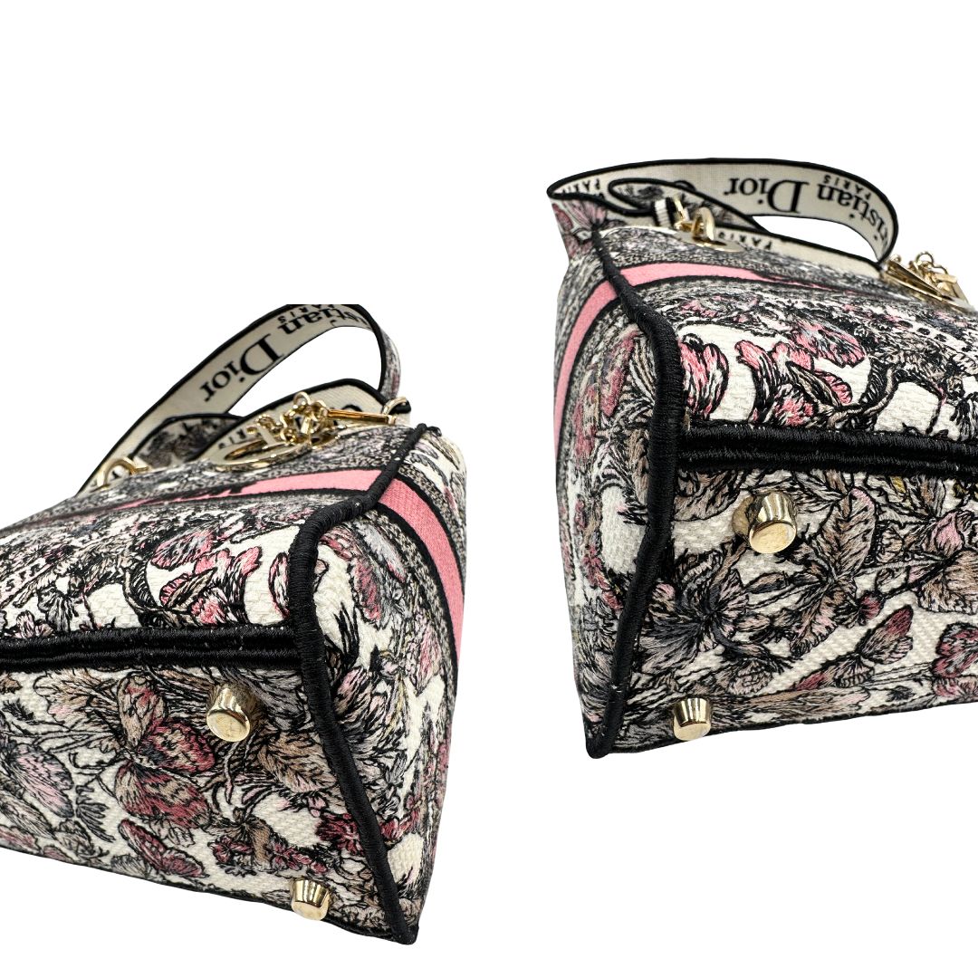 angoli Borsa Dior in realizzata in tessuto jacquard con motivo Toile de Jouy nei toni del nero, beige e rosa e metalleria dorata, munita di due manici rigidi e una tracolla logata amovibile. Da indossare a tracolla o a mano. Completa di dustbag e cartellino, di lusso, usata, originale, ottime condizioni. 
