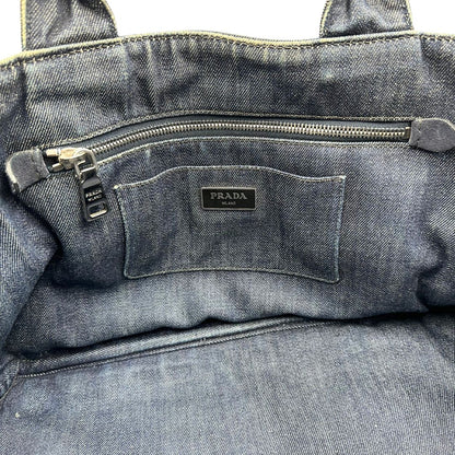interno Borsa Prada in denim blu rifinita con borchie metalliche argentate; munita di una tracolla in tessuto regolabile e amovibile e doppi manici; indossabile a mano o a tracolla. Completa di dustbag, di lusso, originale, buone condizioni. 