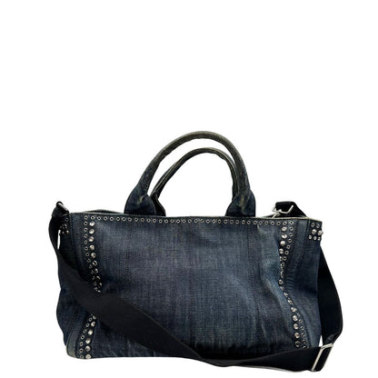 retro Borsa Prada in denim blu rifinita con borchie metalliche argentate; munita di una tracolla in tessuto regolabile e amovibile e doppi manici; indossabile a mano o a tracolla. Completa di dustbag, di lusso, originale, buone condizioni. 