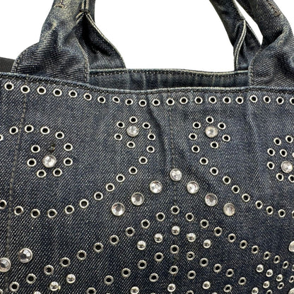 borchie Borsa Prada in denim blu rifinita con borchie metalliche argentate; munita di una tracolla in tessuto regolabile e amovibile e doppi manici; indossabile a mano o a tracolla. Completa di dustbag, di lusso, originale, buone condizioni. 