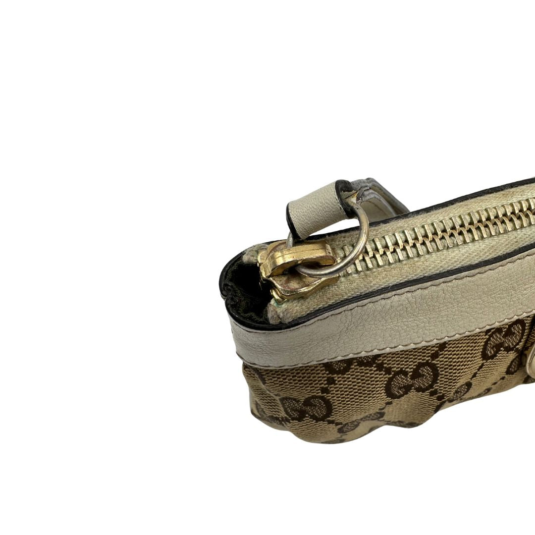 Chiusura di una Pochette Gucci in tessuto Gucci in tessuto GG beige con finiture in pelle bianca e parti metalliche dorate; munita di un polsino, da portare a mano. Completa di scatola. Originale, usata, di lusso, in ottime condizioni.