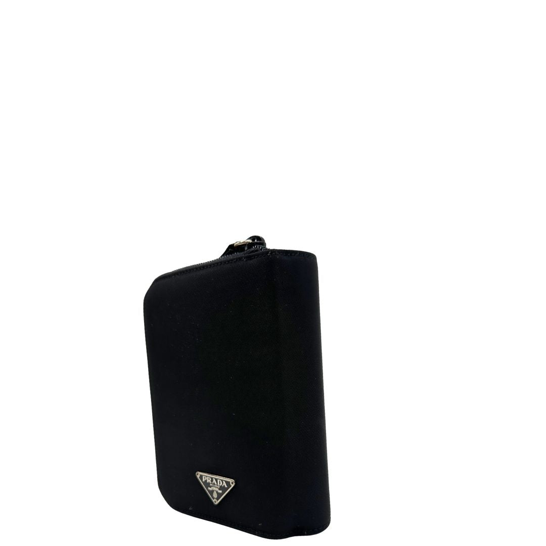 Lato sinistro di un Porta agenda Prada in tessuto nylon nero e finiture in pelle, con parti metalliche argentate; organizzato con portacarte, portapenne e pratico raccoglitore ad anelli per i fogli. Originale, usato, di lusso, in condizioni eccellenti.