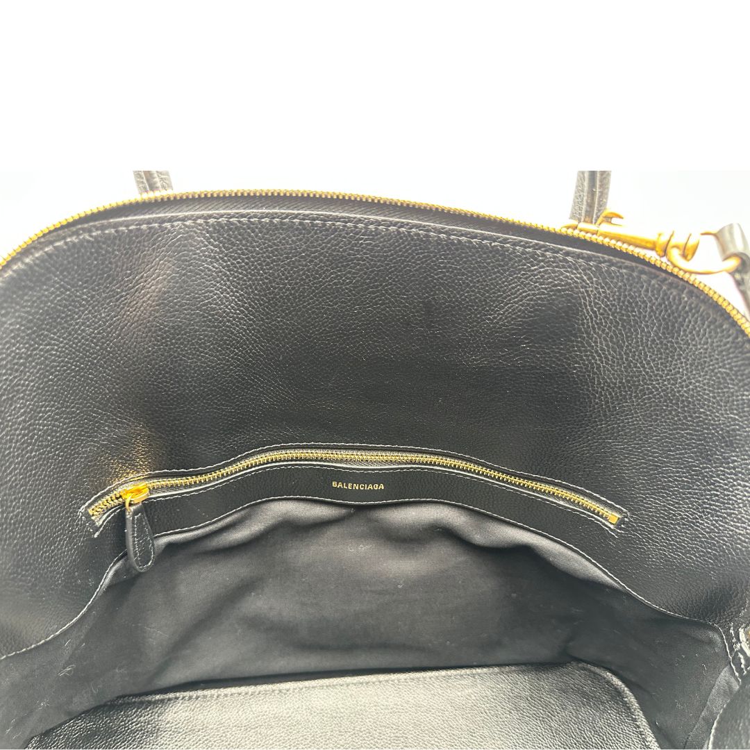Interno di una Borsa Balenciaga in pelle martellata nera con parti metalliche dorate, munita di doppi manici e una tracolla amovibile e regolabile. Completa di dustbag e cartellini, lucchetto e chiavi. Originale, usata, di lusso, in ottime condizioni.