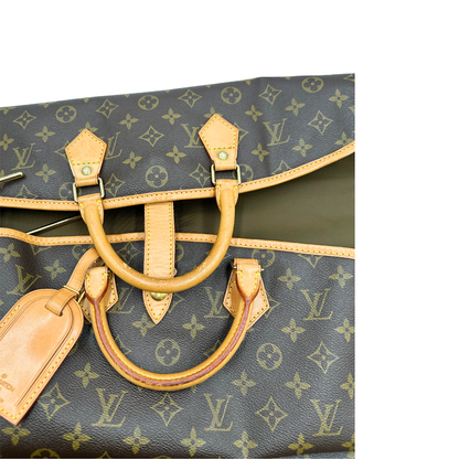 Manici di un Porta abiti in canvas marrone monogram con finiture in vacchetta naturale e parti metalliche dorate; munita di due manici stondati. Completa di due lucchetto, chiavi, tag porta address e una dustbag. Originale, usata, di lusso, in ottime condizioni.