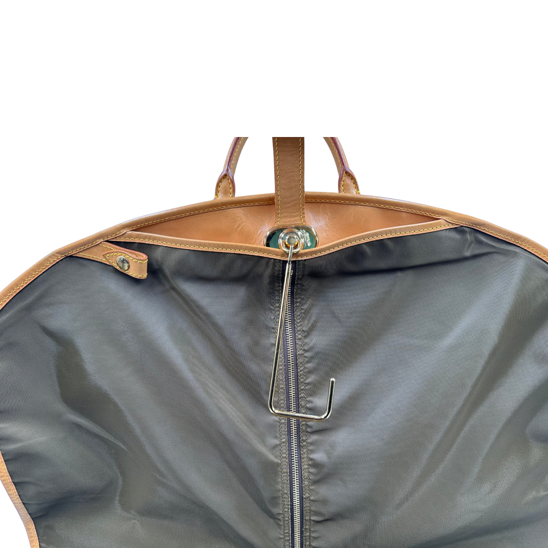 Porta abiti in canvas marrone monogram con finiture in vacchetta naturale e parti metalliche dorate; munita di due manici stondati. Completa di due lucchetto, chiavi, tag porta address e una dustbag. Originale, usata, di lusso, in ottime condizioni.