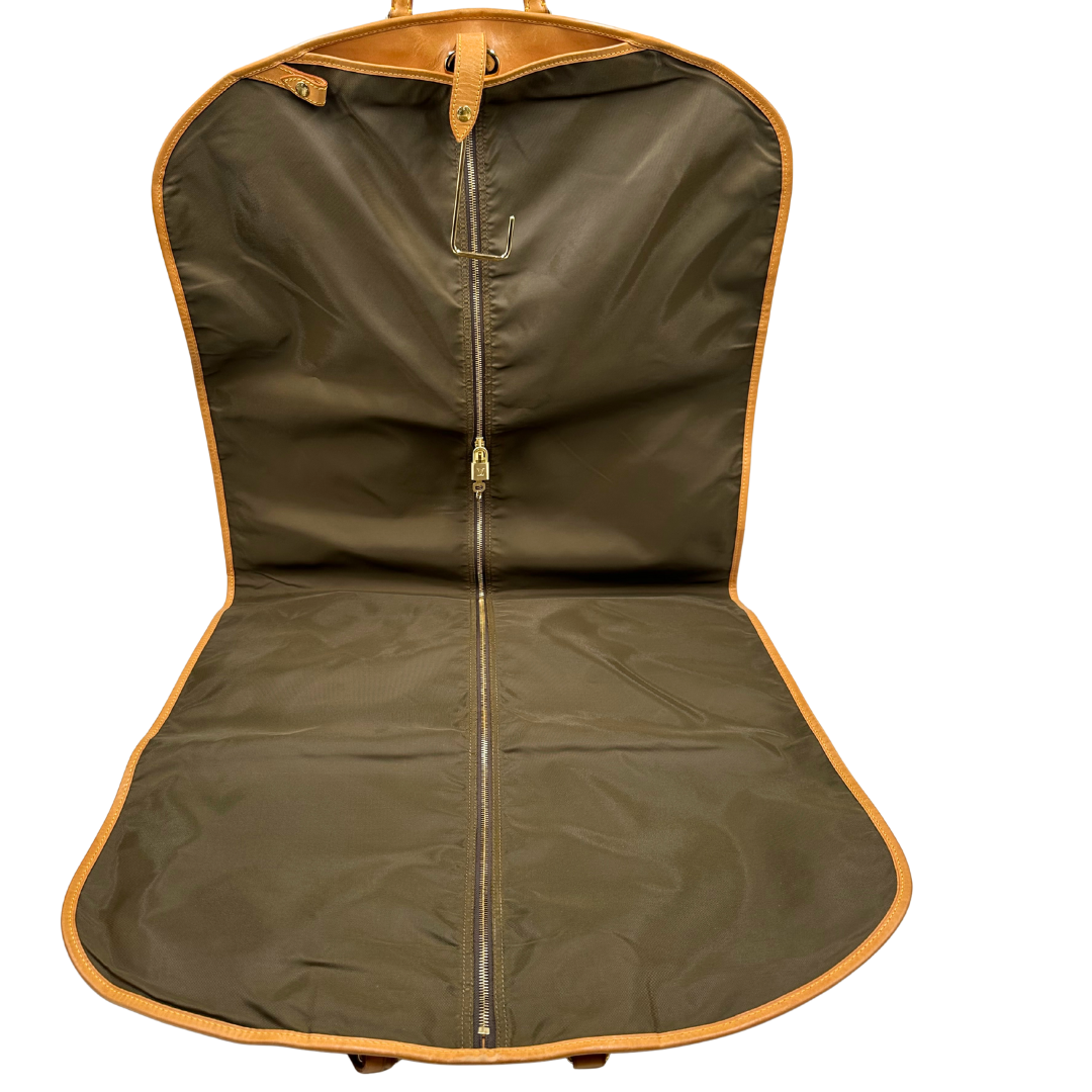 Interno di un Porta abiti in canvas marrone monogram con finiture in vacchetta naturale e parti metalliche dorate; munita di due manici stondati. Completa di due lucchetto, chiavi, tag porta address e una dustbag. Originale, usata, di lusso, in ottime condizioni.