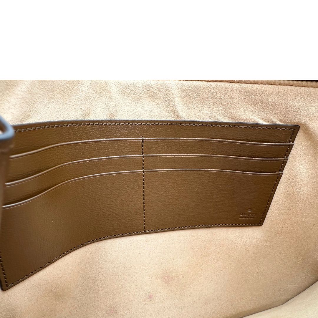 Interno di una Pochette Gucci in canvas GG monogram beige con finiture in pelle marroni e parti metalliche dorate; munita di un polsino in pelle amovibile, indossabile a mano. Originale, usata, di lusso, in ottime condizioni.