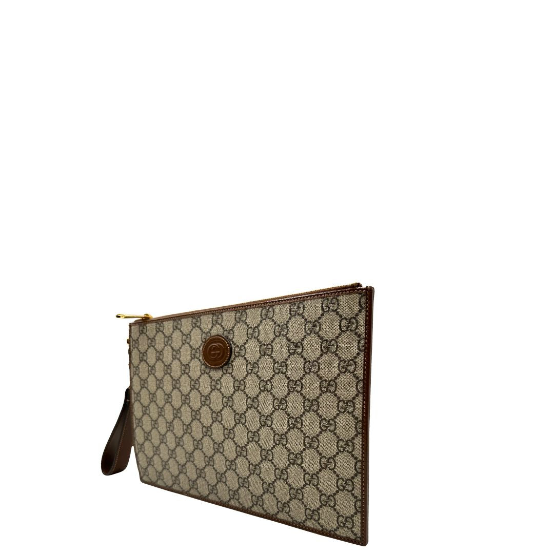 Lato sinstro di una Pochette Gucci in canvas GG monogram beige con finiture in pelle marroni e parti metalliche dorate; munita di un polsino in pelle amovibile, indossabile a mano. Originale, usata, di lusso, in ottime condizioni.