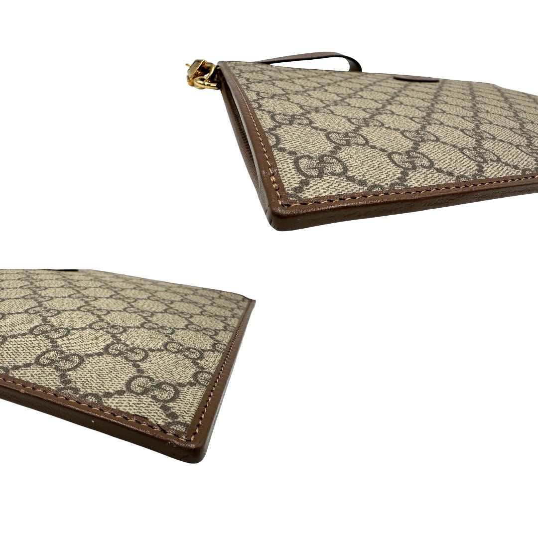 Angoli di una Pochette Gucci in canvas GG monogram beige con finiture in pelle marroni e parti metalliche dorate; munita di un polsino in pelle amovibile, indossabile a mano. Originale, usata, di lusso, in ottime condizioni.
