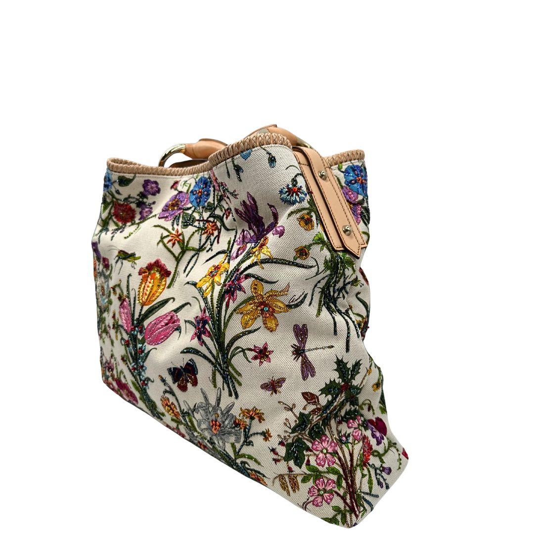 lato Borsa Gucci in tessuto bianco con ricami floreali multicolor, finiture in pelle rosa e parti metalliche dorate; munita di un manico singolo. Completa di dustbag, di lusso, originale, ottime condizioni. 