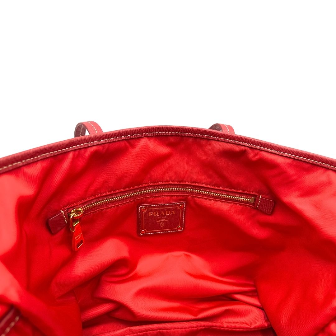 Tasca interna di una Borsa Prada in nylon rosso con parti metalliche dorate e finiture in pelle tono su tono, munita di doppi manici, indossabile a spalla. Completa di dustbag. Originale, usata, di lusso, in ottime condizioni.