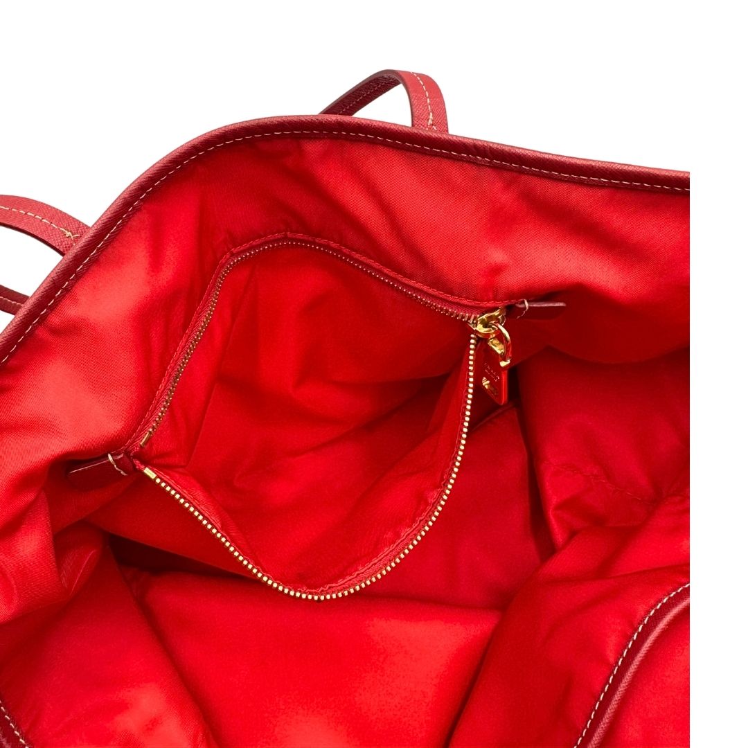 Interno di una Borsa Prada in nylon rosso con parti metalliche dorate e finiture in pelle tono su tono, munita di doppi manici, indossabile a spalla. Completa di dustbag. Originale, usata, di lusso, in ottime condizioni.