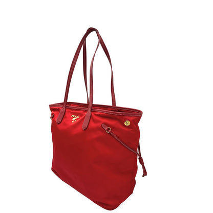 Lato sinistro di una Borsa Prada in nylon rosso con parti metalliche dorate e finiture in pelle tono su tono, munita di doppi manici, indossabile a spalla. Completa di dustbag. Originale, usata, di lusso, in ottime condizioni.
