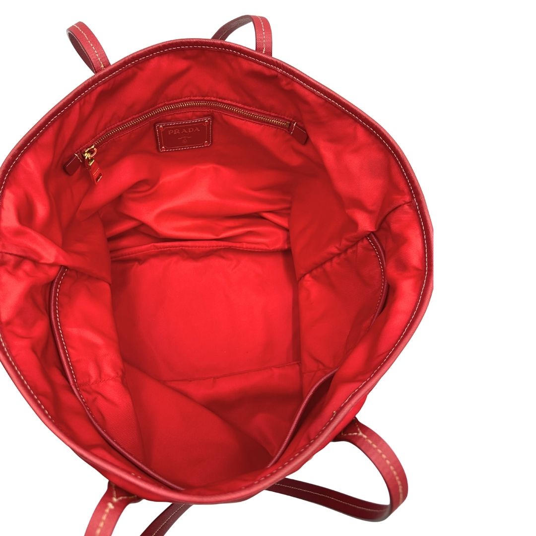 Interno di una Borsa Prada in nylon rosso con parti metalliche dorate e finiture in pelle tono su tono, munita di doppi manici, indossabile a spalla. Completa di dustbag. Originale, usata, di lusso, in ottime condizioni.