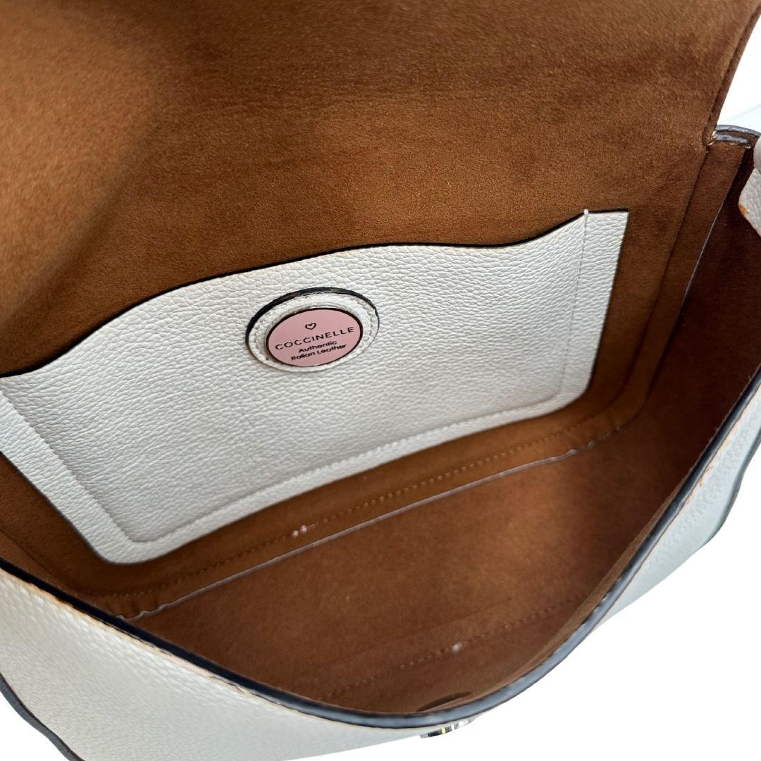 interno  Borsa Coccinelle in pelle martellata bianca con parti metalliche argentate; munita di una tracolla regolabile. Completa di dustbag, di lusso, originale, ottime condizioni, usata. 