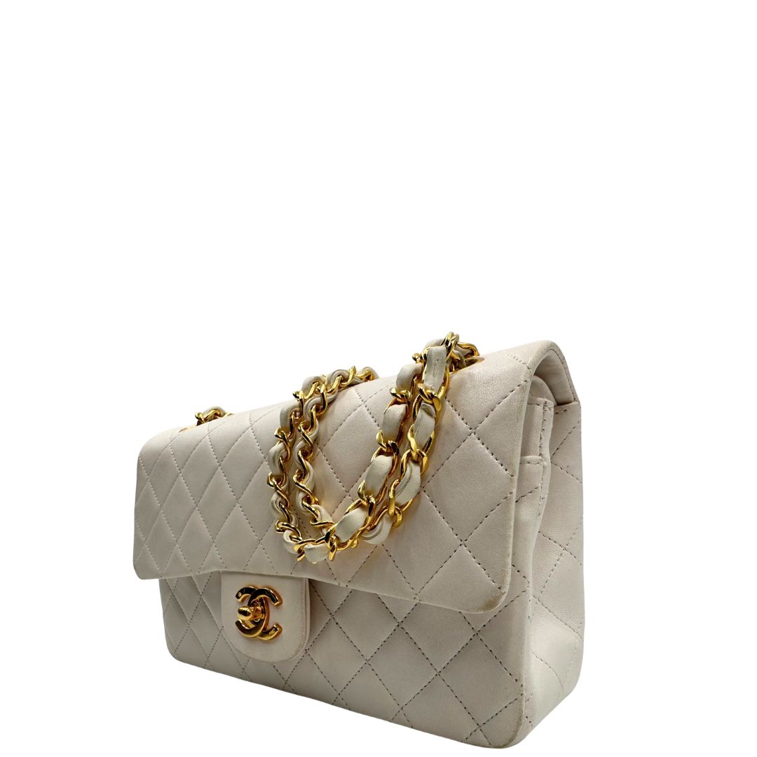 lato  Borsa Chanel in pelle color bianco gesso e parti metalliche dorate; munita di una tracolla scorrevole in catena con intrecci in pelle bianca, indossabile a spalla o a tracolla. Completa di scatola, di lusso, originale, ottime condizioni, usata. 