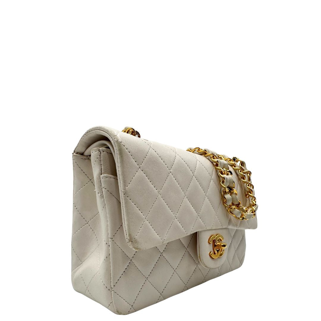 lato  Borsa Chanel in pelle color bianco gesso e parti metalliche dorate; munita di una tracolla scorrevole in catena con intrecci in pelle bianca, indossabile a spalla o a tracolla. Completa di scatola, di lusso, originale, ottime condizioni, usata. 
