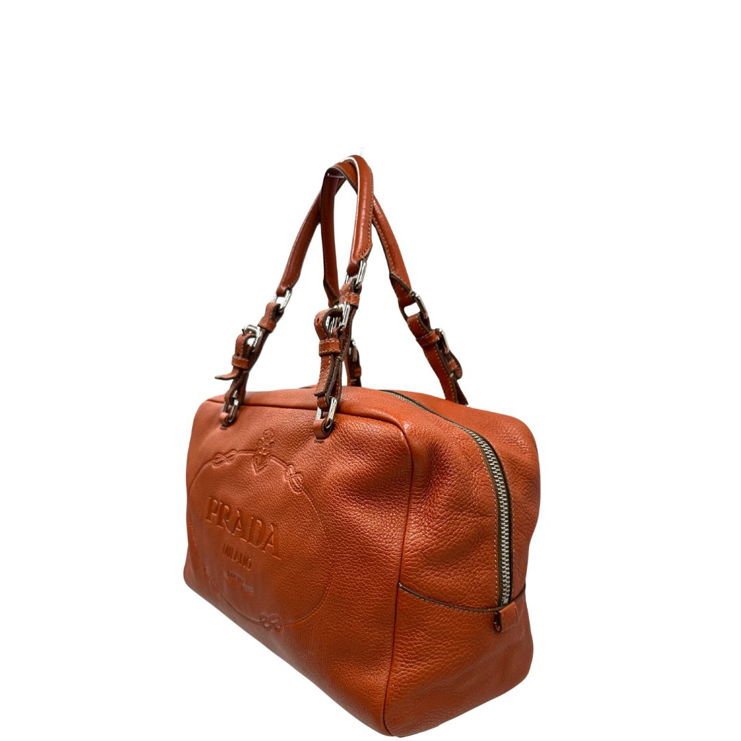 lato Borsa Prada in pelle martellata color cognac con parti metalliche argentate; munita di doppi manici, indossabile a spalla. Completa di lucchetto e chiavi, di lusso, originale, ottime condizioni, usata.