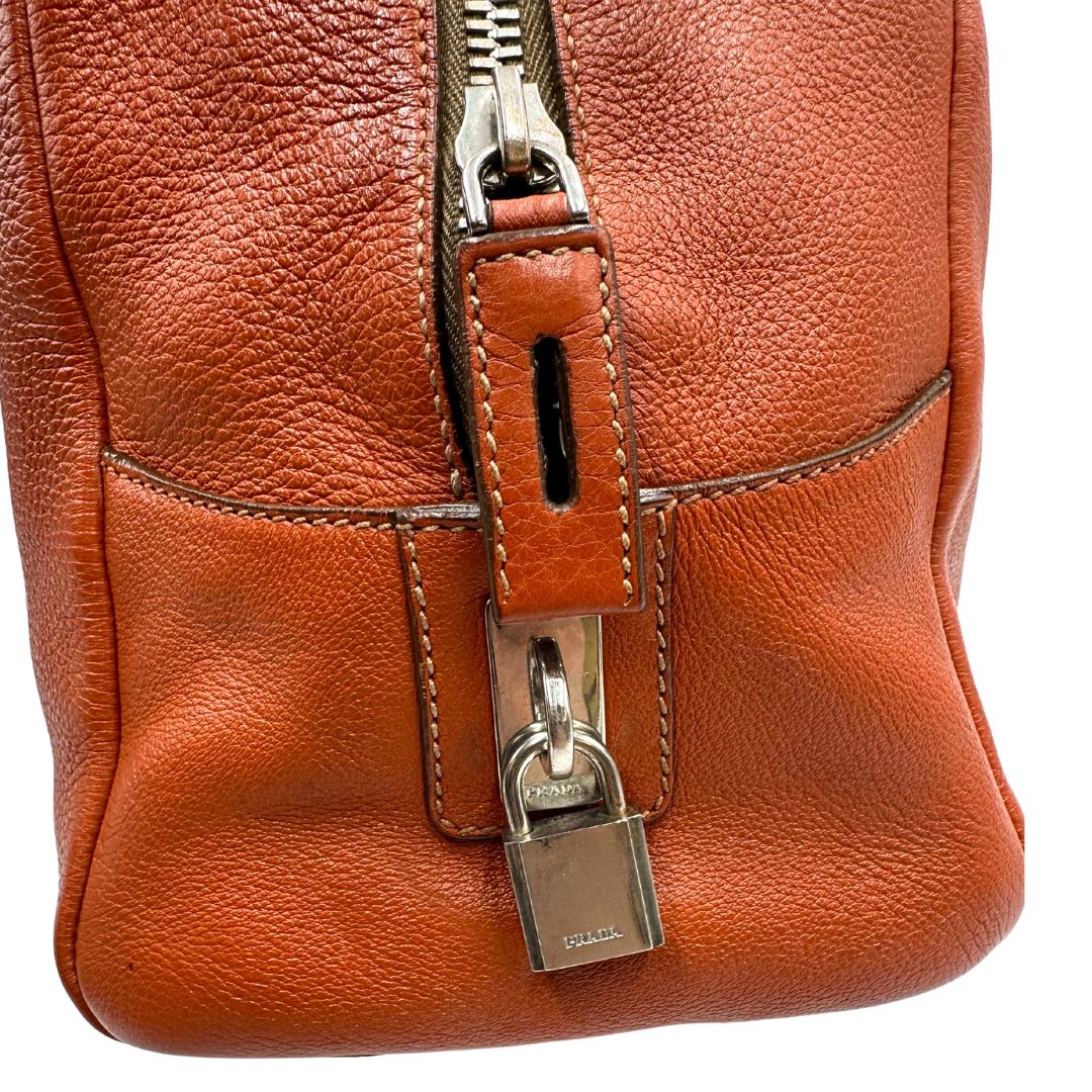 lato  Borsa Prada in pelle martellata color cognac con parti metalliche argentate; munita di doppi manici, indossabile a spalla. Completa di lucchetto e chiavi, di lusso, originale, ottime condizioni, usata. 