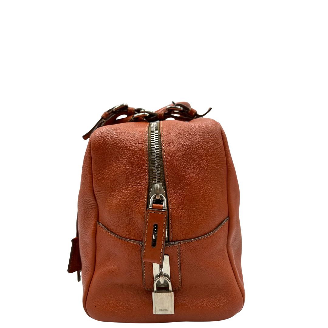 lato  Borsa Prada in pelle martellata color cognac con parti metalliche argentate; munita di doppi manici, indossabile a spalla. Completa di lucchetto e chiavi, di lusso, originale, ottime condizioni, usata. 