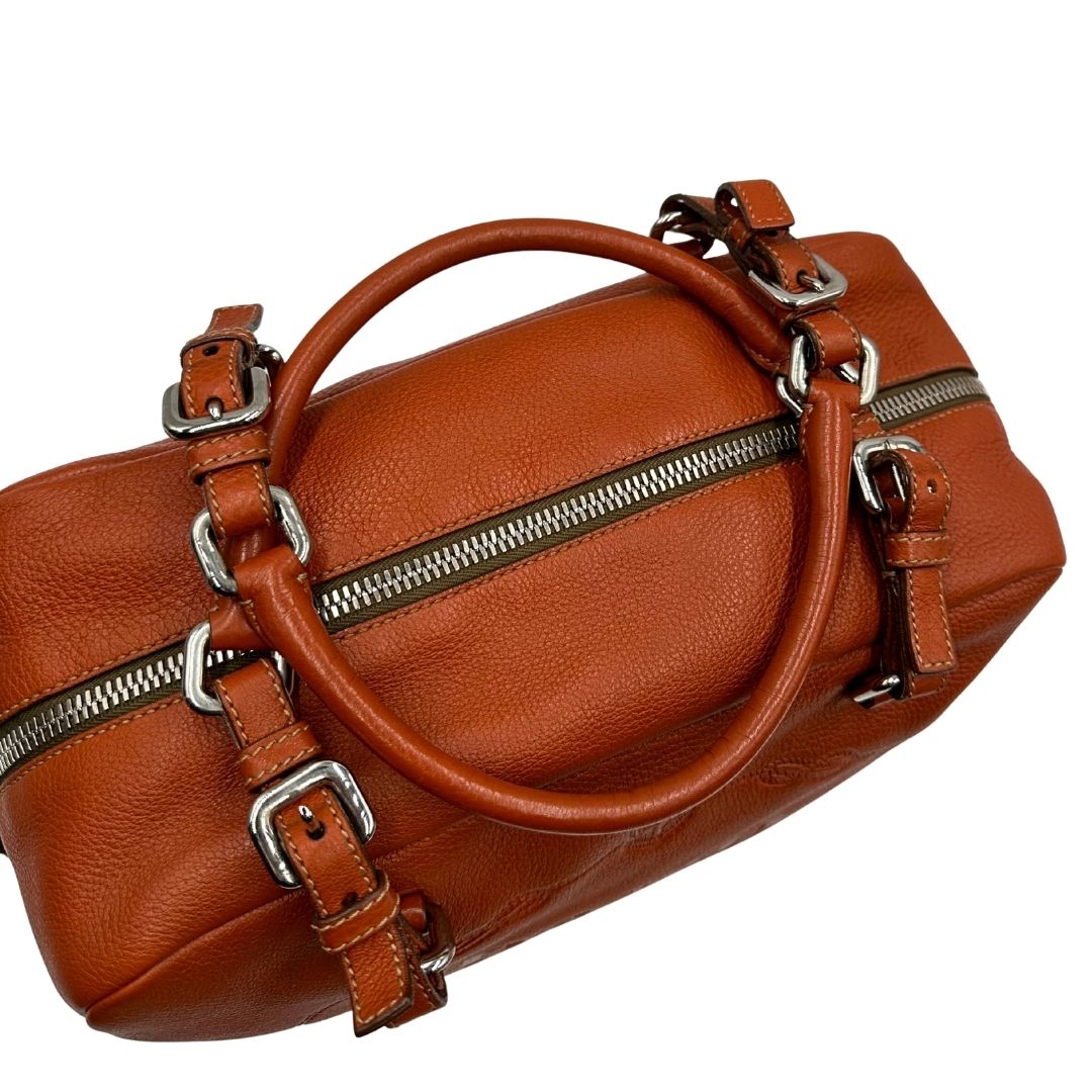 manici  Borsa Prada in pelle martellata color cognac con parti metalliche argentate; munita di doppi manici, indossabile a spalla. Completa di lucchetto e chiavi, di lusso, originale, ottime condizioni, usata. 