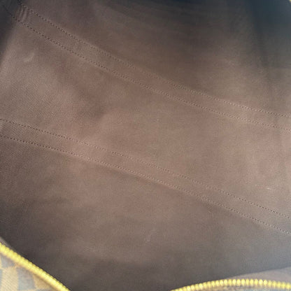 interno del Borsone Louis Vuitton in canvas Damier Ébène marrone con finiture in pelle tono su tono e parti metalliche dorate; munito di doppi manici stondati e una tracolla amovibile e regolabile. Completo di lucchetto, chiavi e dustbag, di lusso, originale, ottime condizioni, usato. 