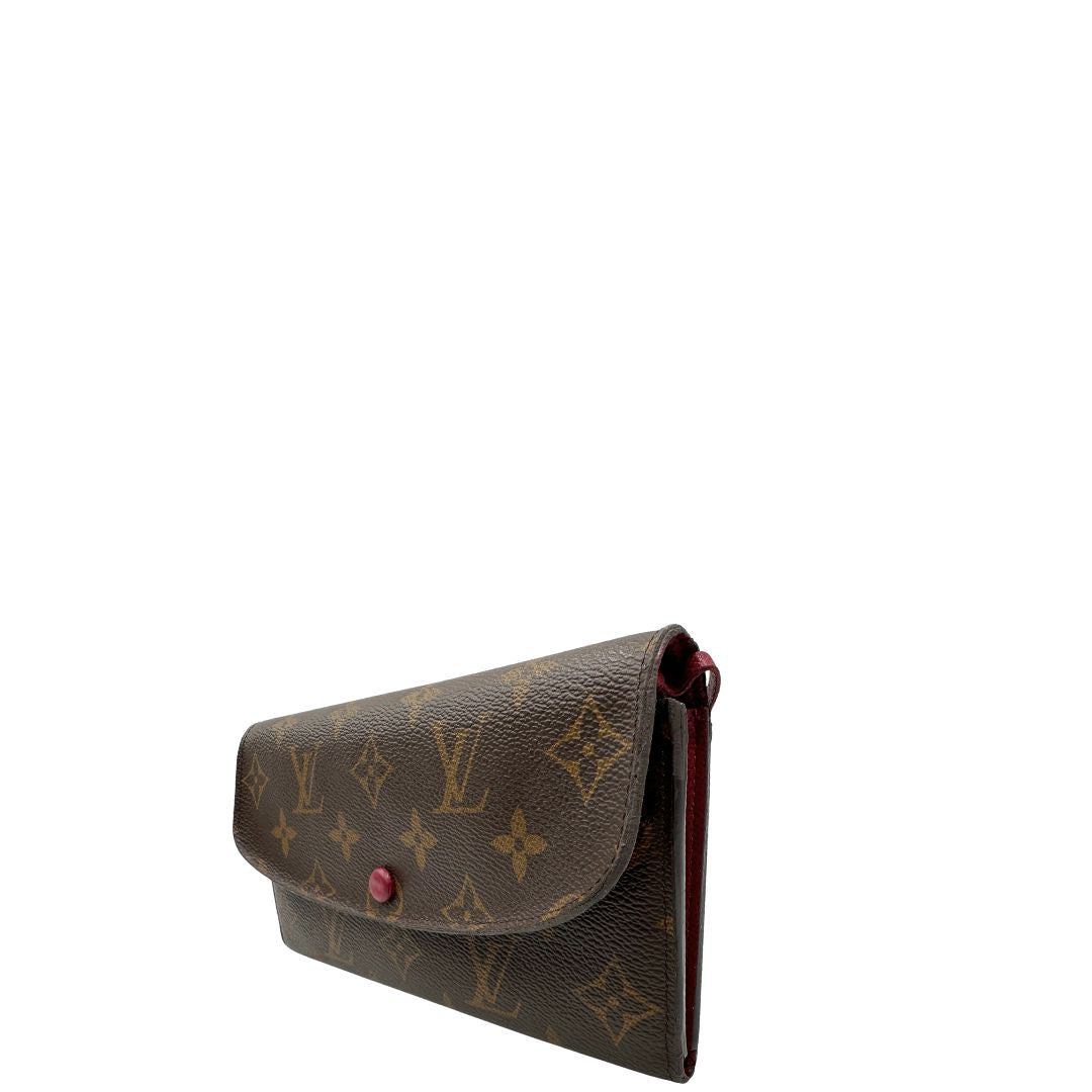 Lato sinistro di un Portafoglio Louis Vuitton Sarah in canvas monogrammato marrone e parti metalliche dorate con bottoncino amaranto. Completo di scatola. Originale, usata, di lusso, in ottime condizioni.