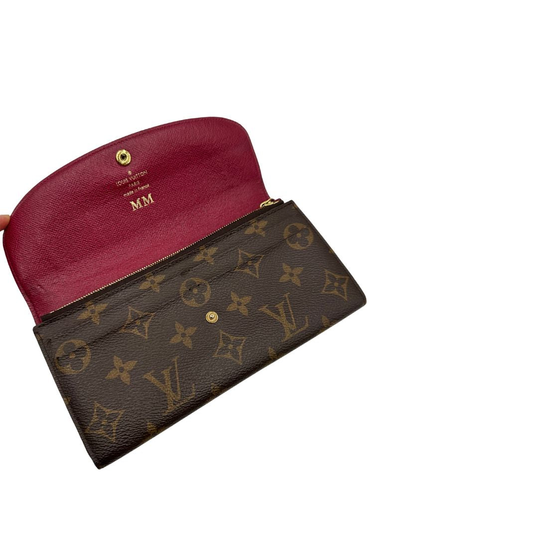 Portafoglio Louis Vuitton Sarah in canvas monogrammato marrone e parti metalliche dorate con bottoncino amaranto. Completo di scatola. Originale, usata, di lusso, in ottime condizioni.