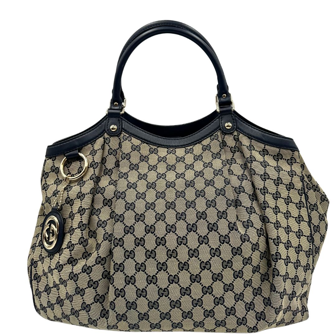 Front di una Borsa Gucci in tessuto beige GG con parti metalliche dorate e parti in pelle color blu notte; munita di doppi manici stondati. Completa di dustbag. Originale, usata, di lusso, in ottime condizioni.