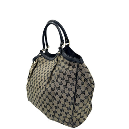Lato sinistro di una Borsa Gucci in tessuto beige GG con parti metalliche dorate e parti in pelle color blu notte; munita di doppi manici stondati. Completa di dustbag. Originale, usata, di lusso, in ottime condizioni.