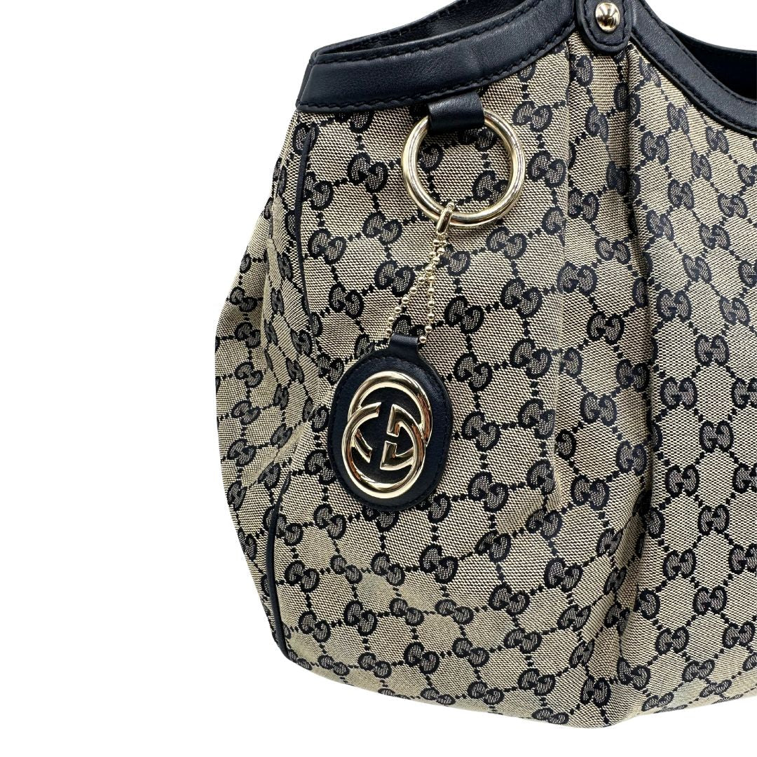 Borsa Gucci in tessuto beige GG con parti metalliche dorate e parti in pelle color blu notte; munita di doppi manici stondati. Completa di dustbag. Originale, usata, di lusso, in ottime condizioni.