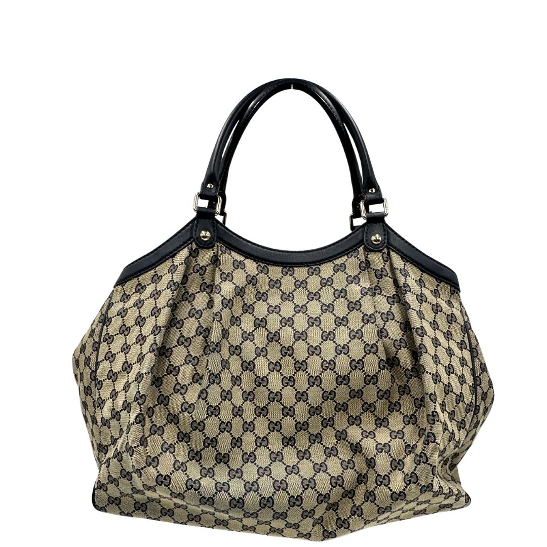 Retro di una Borsa Gucci in tessuto beige GG con parti metalliche dorate e parti in pelle color blu notte; munita di doppi manici stondati. Completa di dustbag. Originale, usata, di lusso, in ottime condizioni.