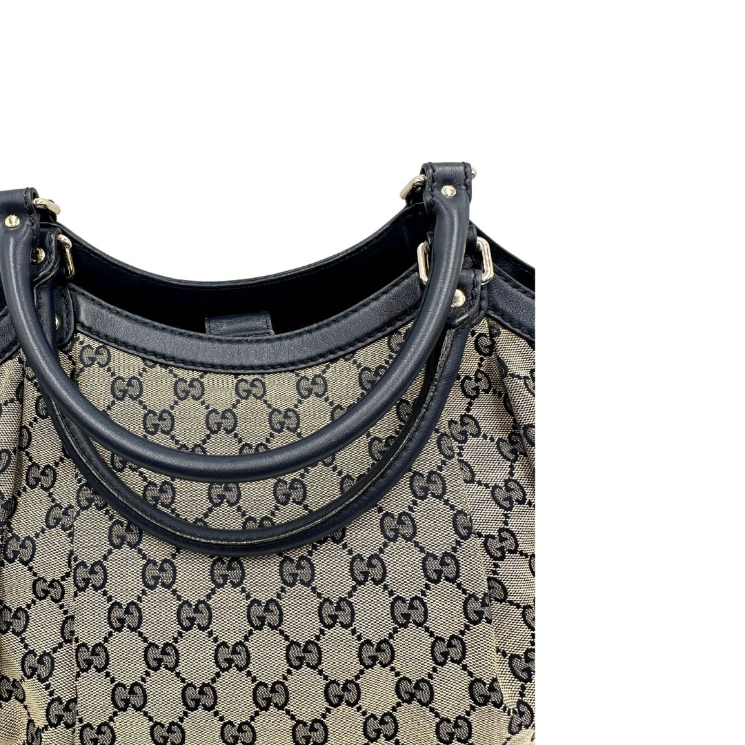 Manici di una Borsa Gucci in tessuto beige GG con parti metalliche dorate e parti in pelle color blu notte; munita di doppi manici stondati. Completa di dustbag. Originale, usata, di lusso, in ottime condizioni.