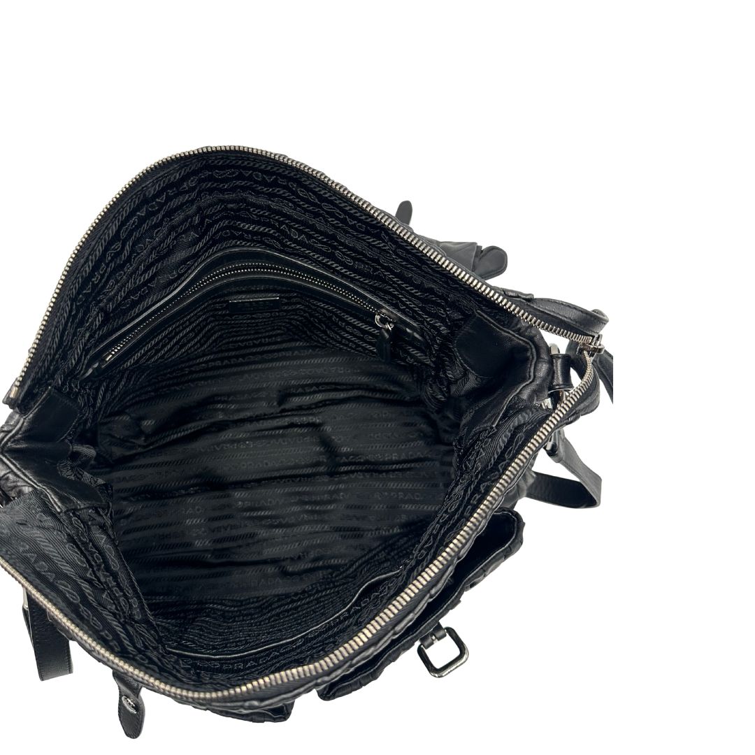 Interno di una Borsa Prada in tessuto nylon goffrato nero con parti metalliche argentate e inserti in pelle tono su tono, munita di una tracolla regolabile e amovibile. Completa di dustbag. Originale, usata, di lusso, in ottime condizioni.