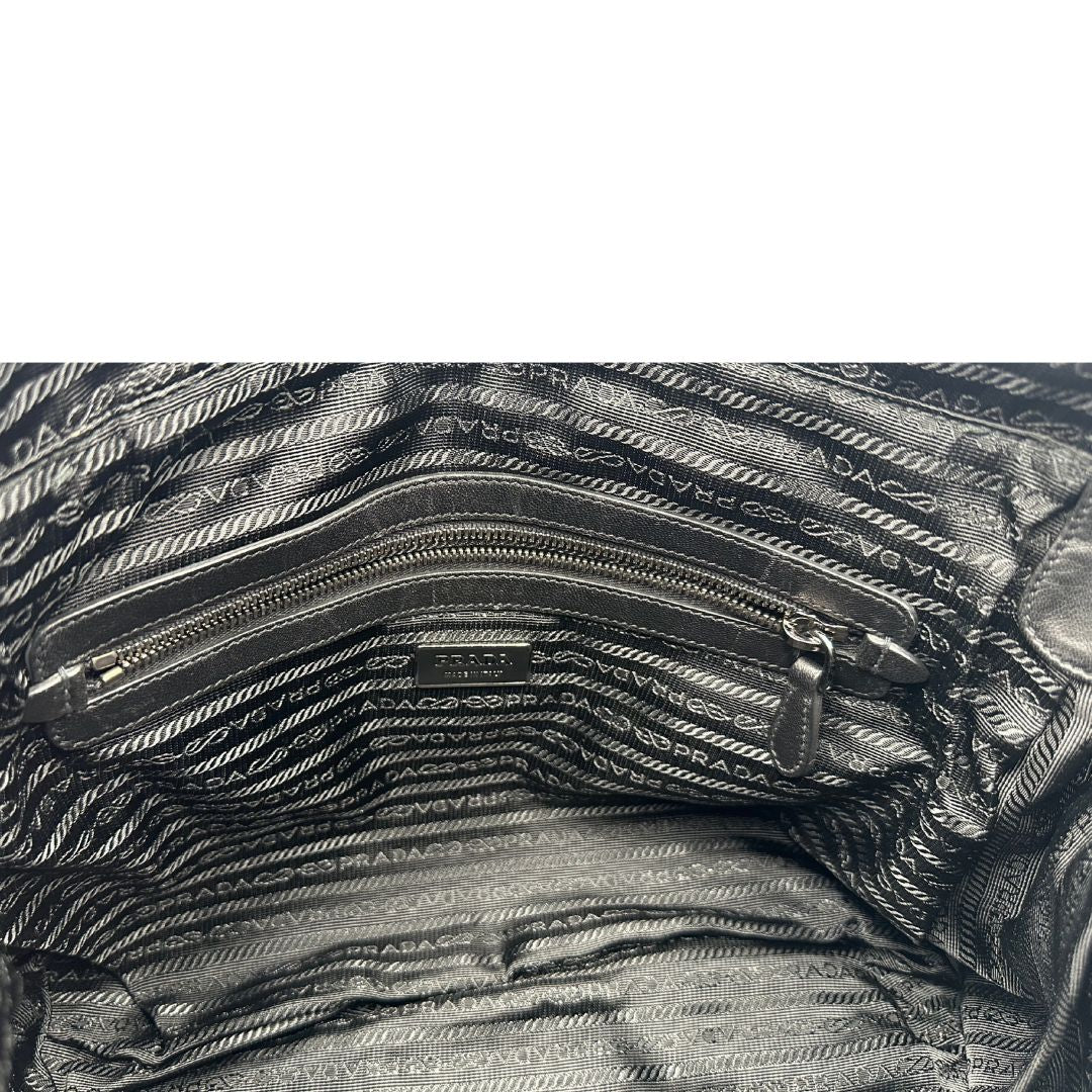Interno di una Borsa Prada in tessuto nylon goffrato nero con parti metalliche argentate e inserti in pelle tono su tono, munita di una tracolla regolabile e amovibile. Completa di dustbag. Originale, usata, di lusso, in ottime condizioni.